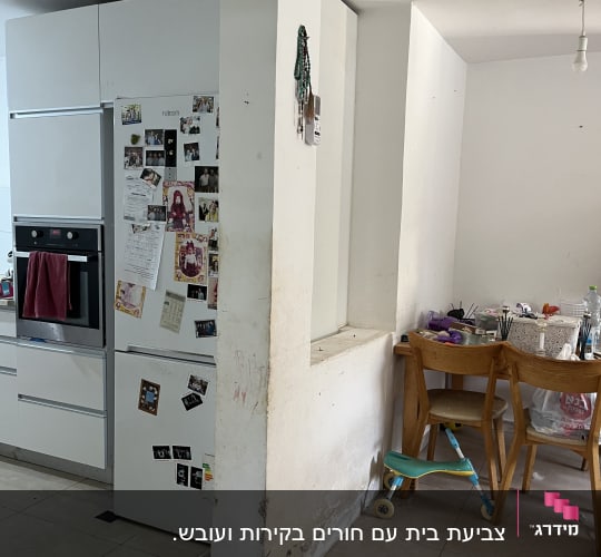 קיר עם סימני לכלוך וציוד צביעה על שולחן